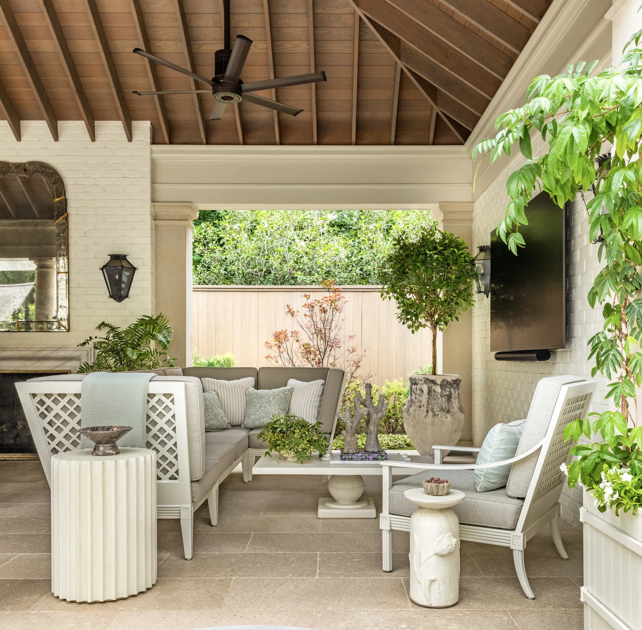 Outdoor living room with lattice-back seating, a fireplace, and mounted television