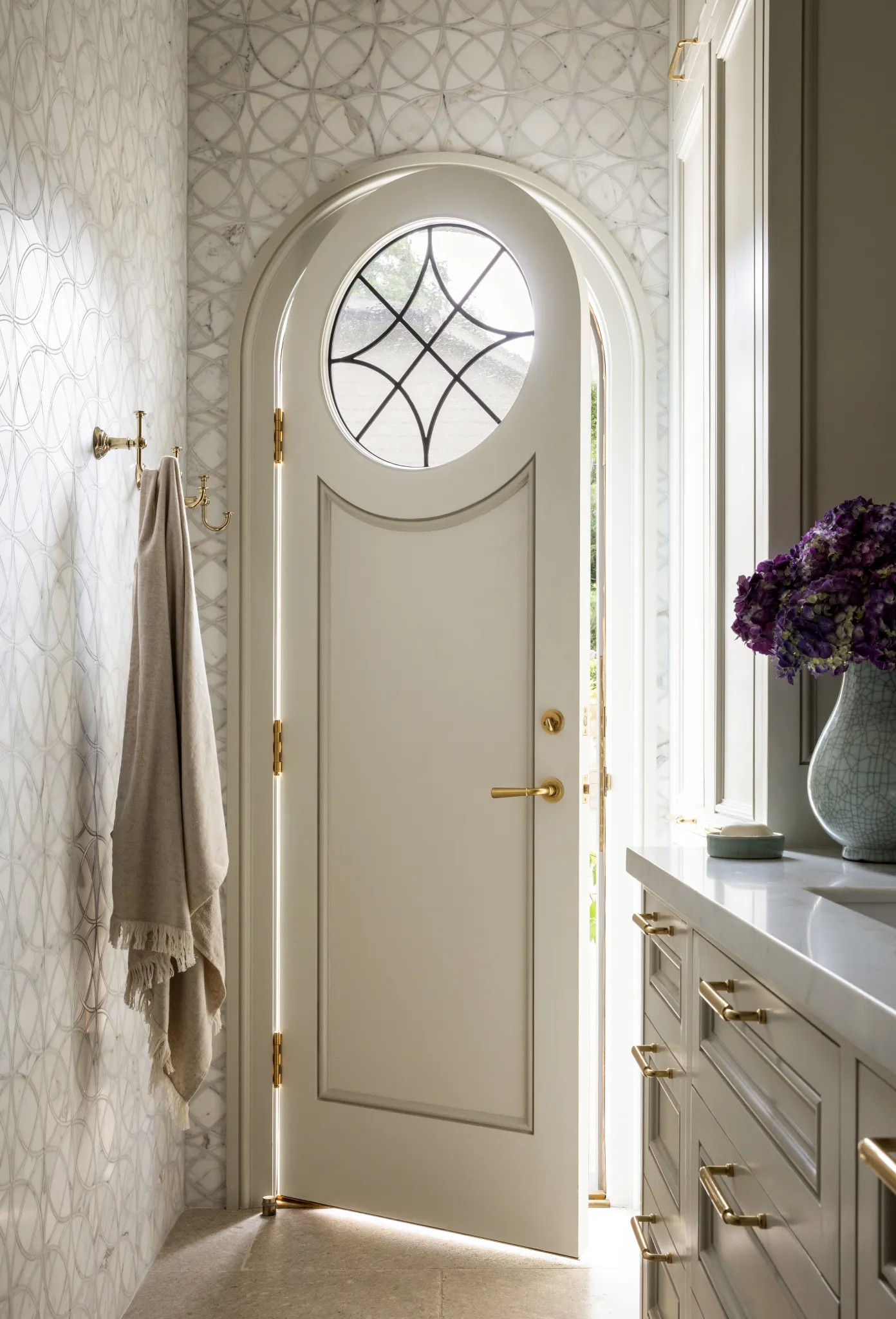 Arched door with a leaded oculus window set in patterned marble tile